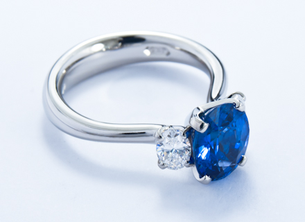 Four claw three stone platinum ring with an oval blue sapphire and diamonds