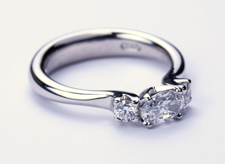 Four claw three stone platinum ring with oval cut and round brilliant cut diamonds