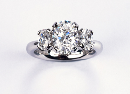 Four claw three stone platinum ring with oval brilliant cut diamonds